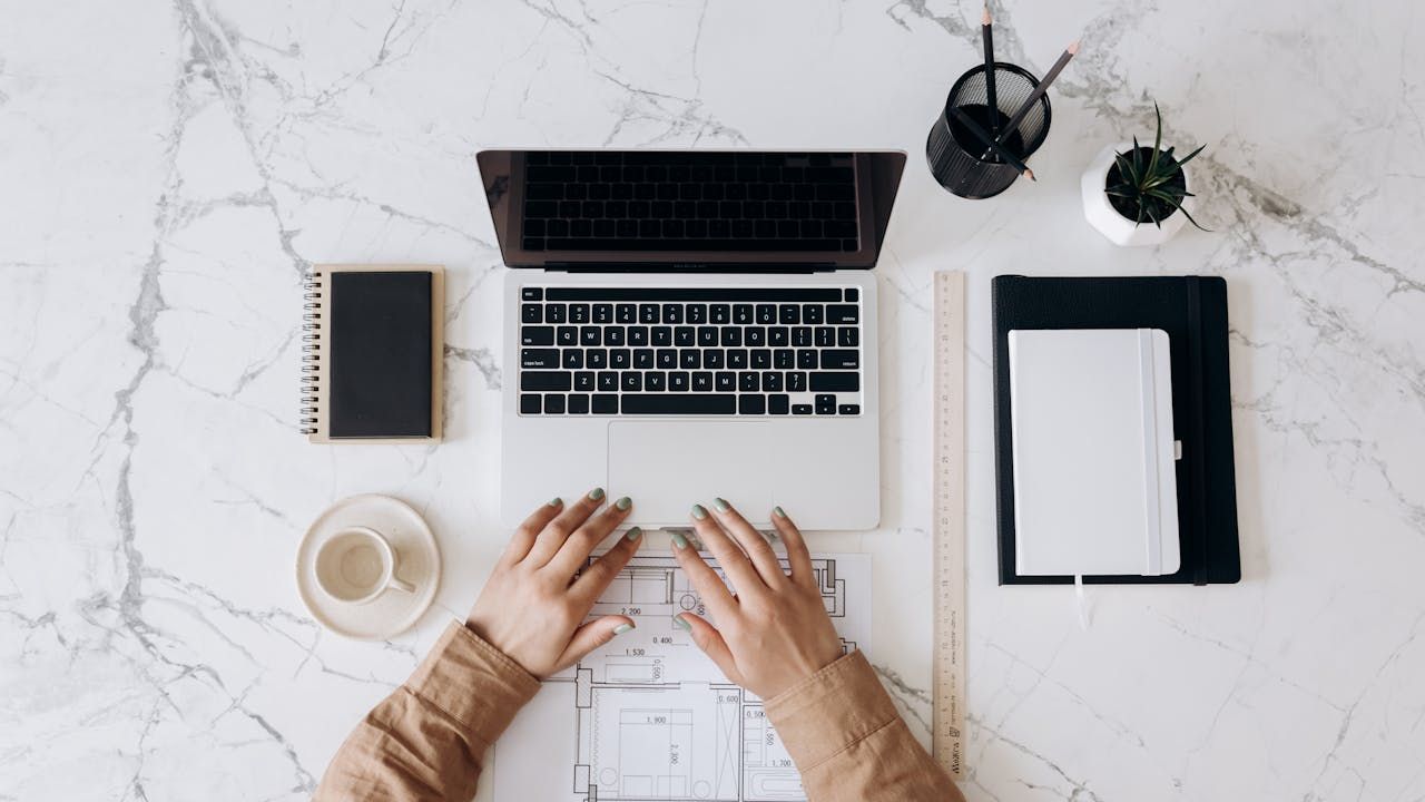 Apo VA social media manager working on a laptop beside a white ceramic mug
